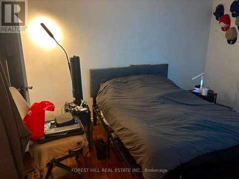 A bedroom with a bed, desk, and lamp.