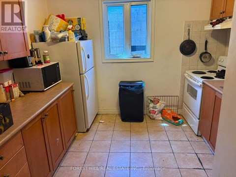 A kitchen with a refrigerator, microwave, and oven.