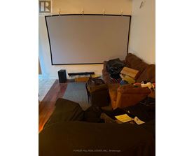 A living room with a couch, a chair, and a projector screen.