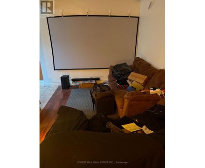 A living room with a couch, a chair, and a projector screen.