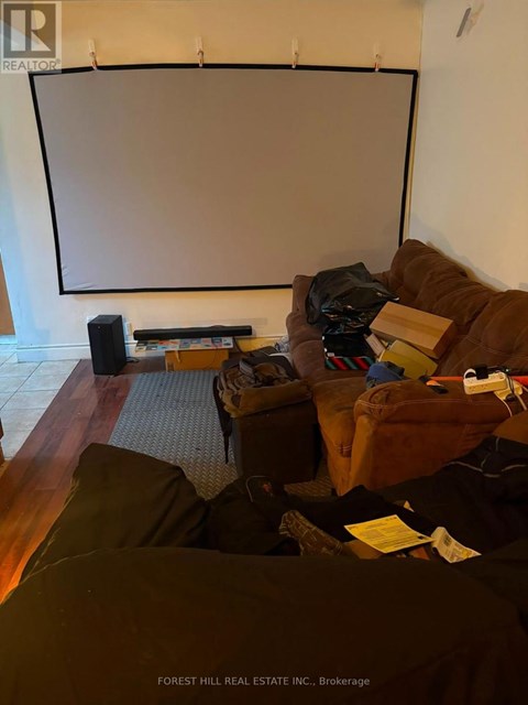 A living room with a couch, a chair, and a projector screen.