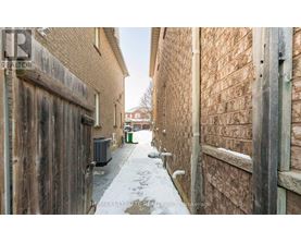 A narrow alley with brick walls and a wooden door on the left.