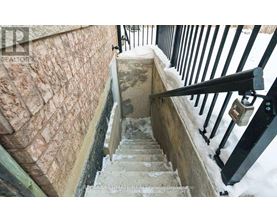 A staircase with a stone wall and a black railing.