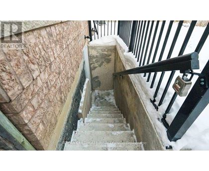 A staircase with a stone wall and a black railing.