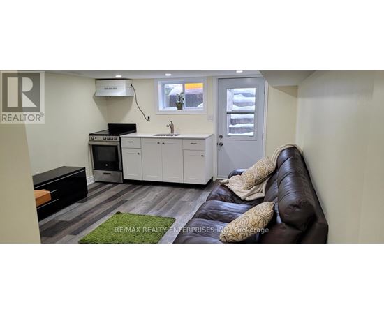 A small, modern kitchen with a black couch.