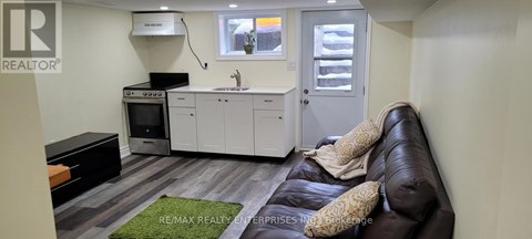 A small, modern kitchen with a black couch.