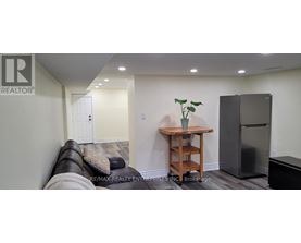 A living room with a couch, a table, and a refrigerator.
