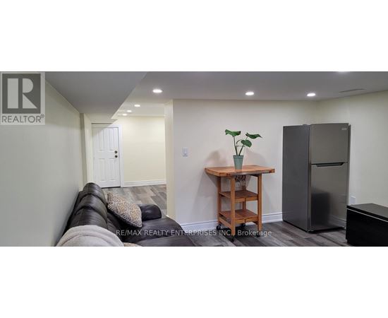 A living room with a couch, a table, and a refrigerator.