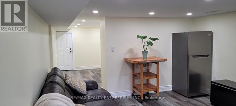 A living room with a couch, a table, and a refrigerator.