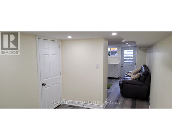 A white door is in a hallway with a couch and a chair.
