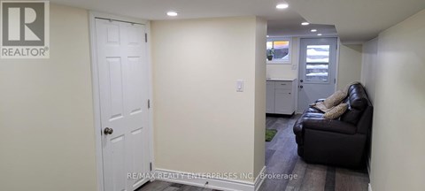 A white door is in a hallway with a couch and a chair.