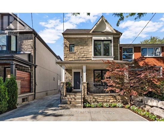 A house with a stone facade and a front porch is surrounded by a well-kept garden.