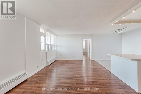A spacious room with wooden floors and white walls.