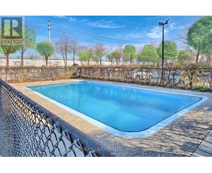 A pool surrounded by a fence with a realtor sign in the background.