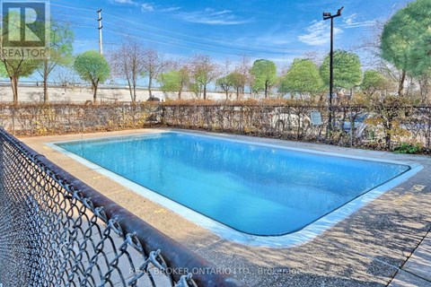 A pool surrounded by a fence with a realtor sign in the background.