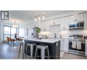 A modern kitchen with stainless steel appliances and a dining area with chairs.