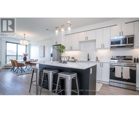 A modern kitchen with stainless steel appliances and a dining area with chairs.