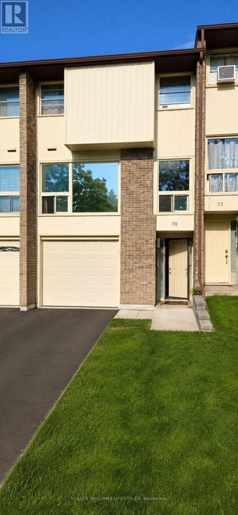 A building with a brown roof and beige walls with windows and a garage door.