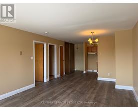 A spacious room with wooden floors and a chandelier.