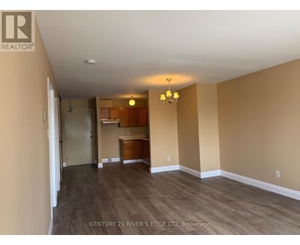 A room with a kitchenette and a dining table in the middle.