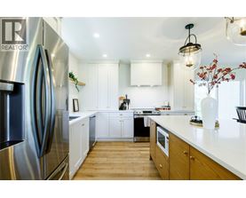 A modern kitchen with a stainless steel refrigerator and wooden floors.