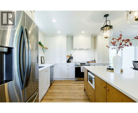 A modern kitchen with a stainless steel refrigerator and wooden floors.