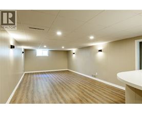 A spacious room with wooden flooring and white walls.