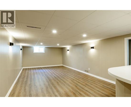 A spacious room with wooden flooring and white walls.