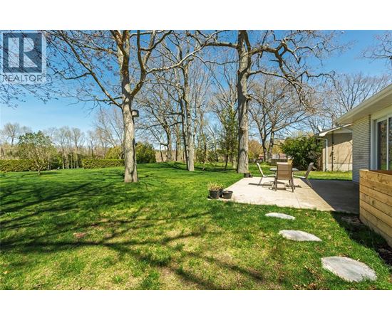A backyard with a lawn, trees, and a patio area.