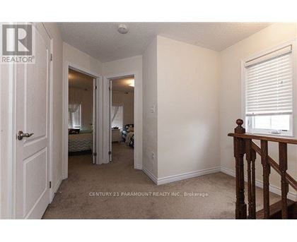 A bedroom with a bed, a window with blinds, and a wooden staircase.