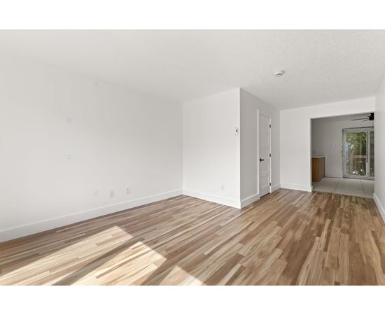 A room with wooden flooring and white walls.
