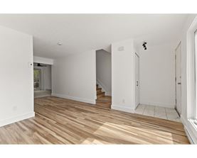 A room with wooden flooring and white walls.