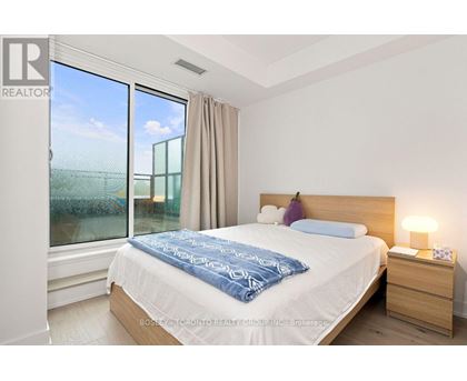 A bedroom with a large bed and a window overlooking a field.