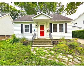 A small white house with a red door and a stone pathway leading to the front door.
