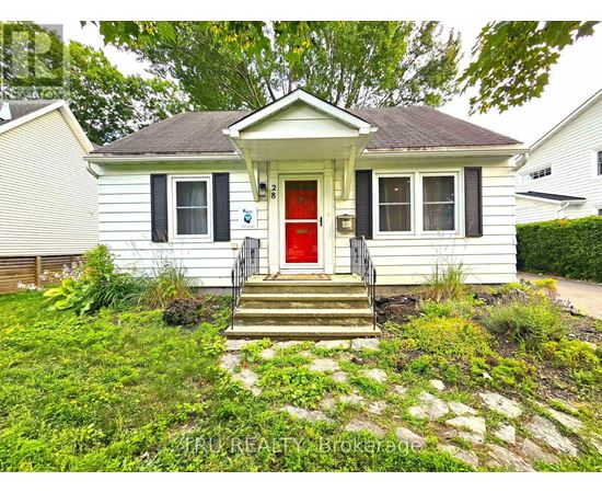 A small white house with a red door and a stone pathway leading to the front door.