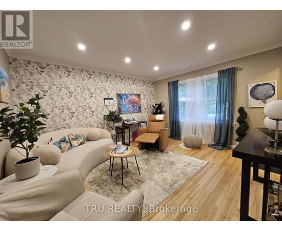 A living room with a couch, a chair, a table, and a painting on the wall.