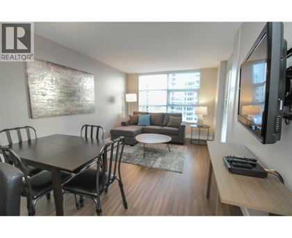 A living room with a grey couch, a coffee table, and a dining table with chairs.