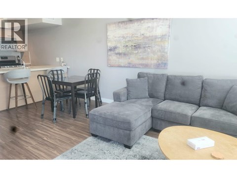A living room with a grey couch, a coffee table, and a dining table with chairs.