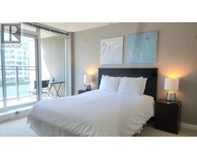 A bedroom with a large bed and a window overlooking a cityscape.