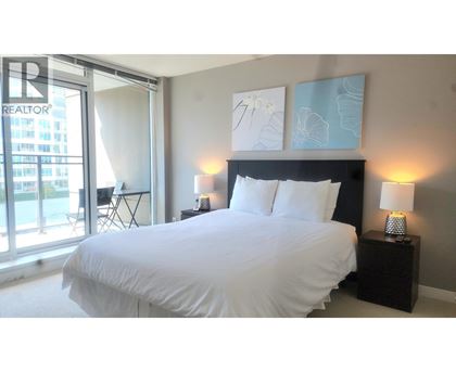 A bedroom with a large bed and a window overlooking a cityscape.