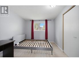 A bedroom with a bed, nightstand, and window with red curtains.