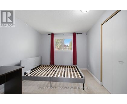 A bedroom with a bed, nightstand, and window with red curtains.