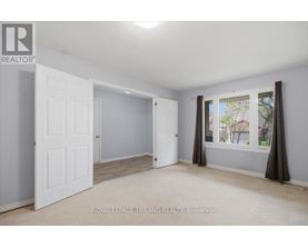 A white door is open to a room with a window showing a view of a house.