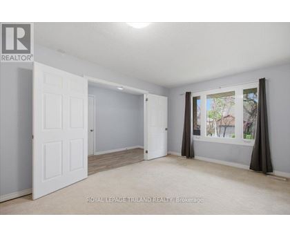 A white door is open to a room with a window showing a view of a house.