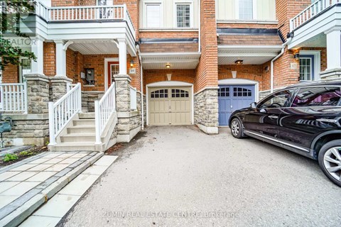 A black car is parked in front of a house with a garage.