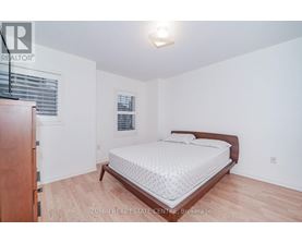 A bedroom with a bed, wooden dresser, and window.