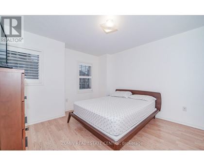 A bedroom with a bed, wooden dresser, and window.