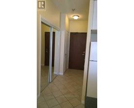 A hallway with a white refrigerator on the right side.