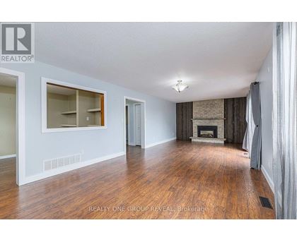 A spacious room with wood flooring and a fireplace.