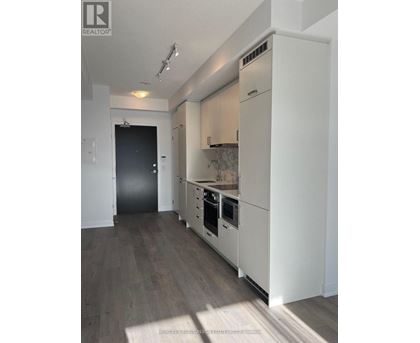 A modern kitchen with white cabinets and a black door.